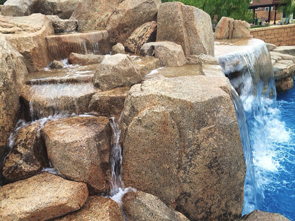 Water cascading over concrete rocks that look like they came straight from the desert.