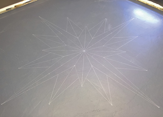 Chalk drawing of a compass rose on a floor.