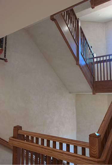 Four story stair well with wood hand rails in a seminary is coated off white with a product from Pure Texture.