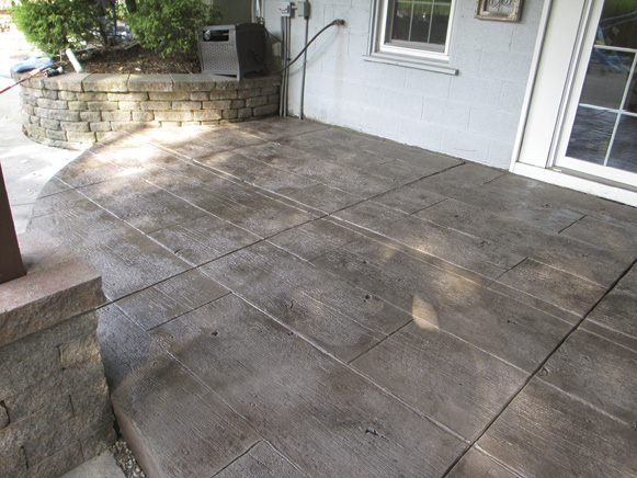 Contractor Jim Boyce created this rustic wood-looking patio by stamping an overlay with Butterfields Gilpins Fall Bridge Plank pattern. The topping was colored with Butterfields Burnished Taupe and antiqued with Storm Gray and Deep Charcoal.