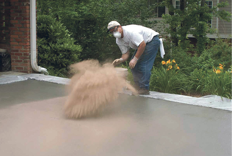 Concrete contractor wearing appropriated personal safety protection while throwing color hardener for concrete.