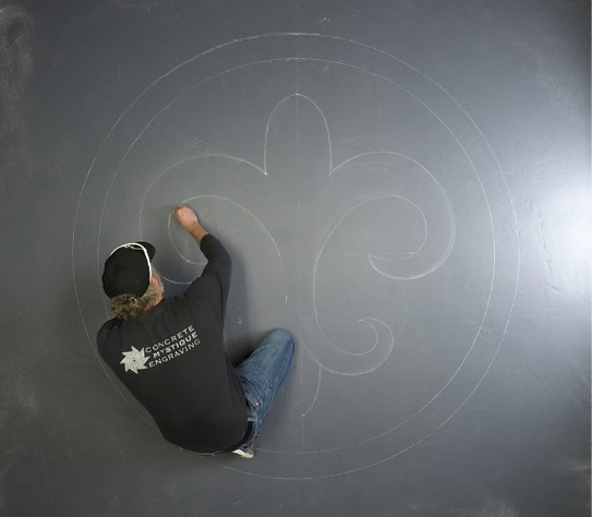 Finishing off the curves of a fleur-de-lis drawing on a concrete floor.
