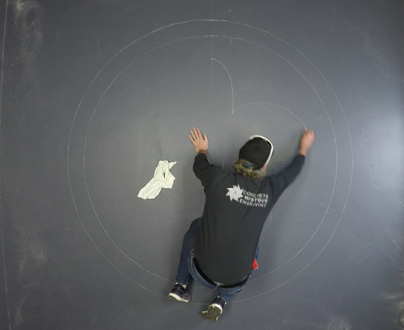 How to draw a circle on a concrete floor using a chalk box and string.