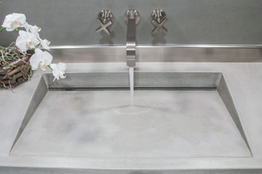 Square sloped concrete sink in a floating vanity design.