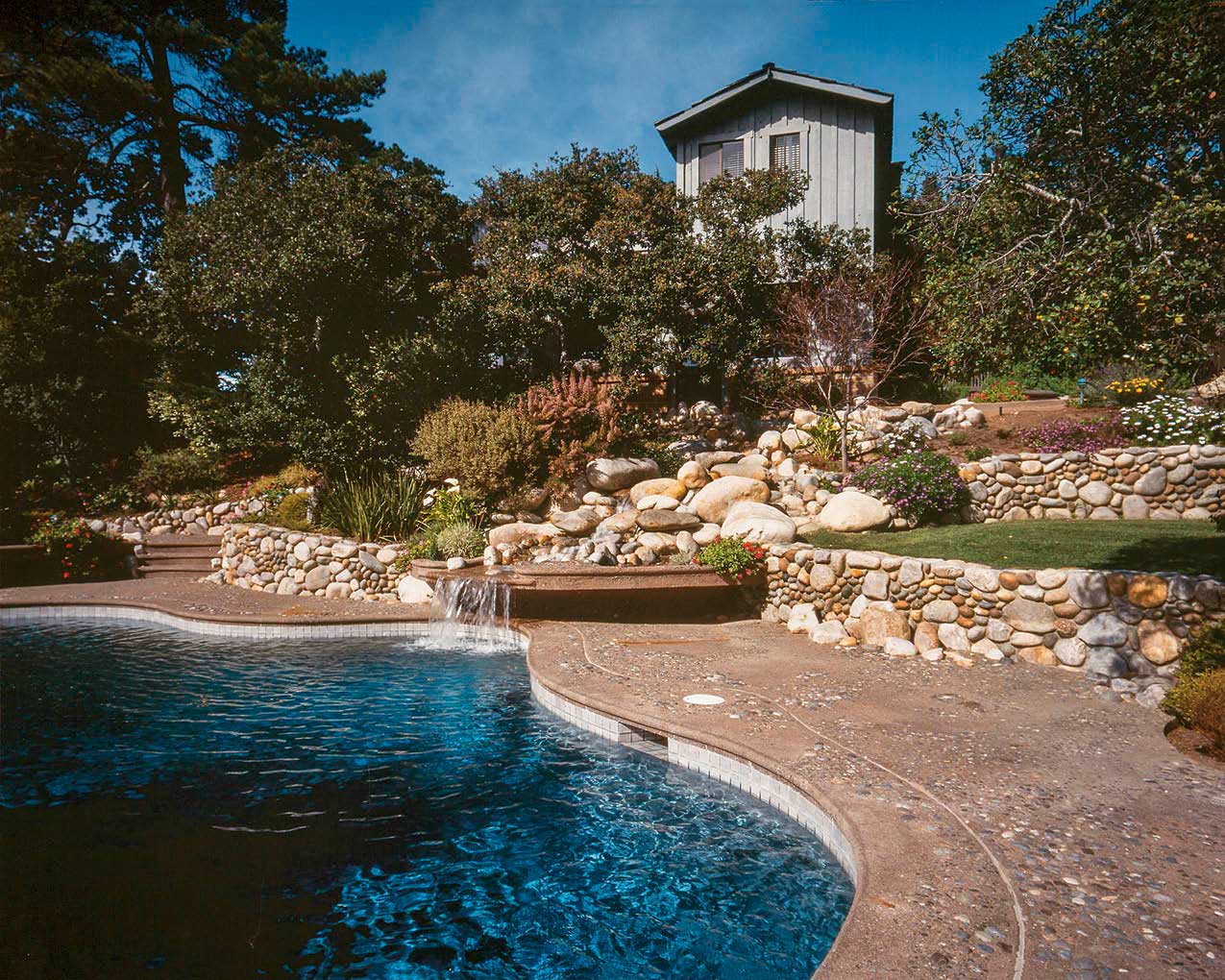 Aggregates take center stage in this pool setting in Carmel, California. River rocks ranging in size from 3 feet to 1/8 inch in diameter create a cliffside/waterfall feature, while natural rock aggregate sculpted and rounded by water creates a streambed effect on the pool deck, with sand washes and clusters of rock. The concretes tan integral color harmonizes with the aggregate. Photos courtesy of Tom Ralston Concrete