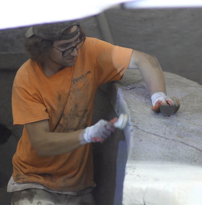 Jacob Winget sanding the edge of the concrete cap.