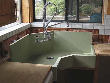 To solve a problem that was rotting cabinets and wetting the kitchen floor, Nathan Hake of Cranium Construction in Manchester, California, designed this corner sink for a project that also involved custom terrazzo-blended counters.