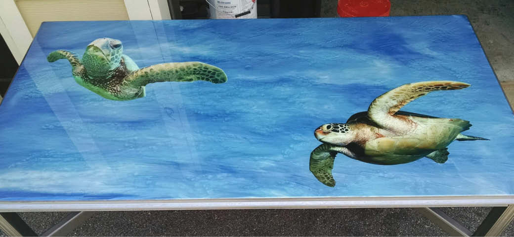 Detailed turtles on a blue concrete metallic epoxy coated table.