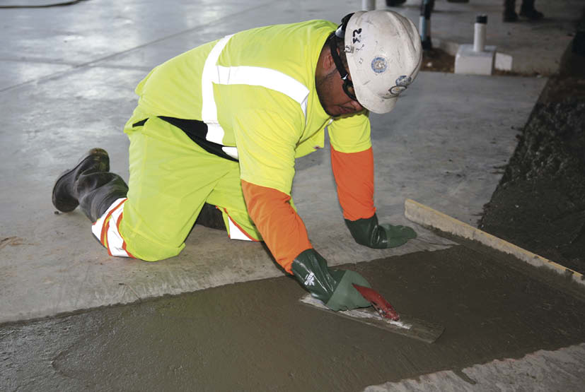 Anyone who works with concrete knows it can do a slow burn on exposed skin. Thats why this well-protected worker has gloves, boots, a long-sleeved shirt and eye protection. The reflective gear and hardhat protect against unseen dangers.