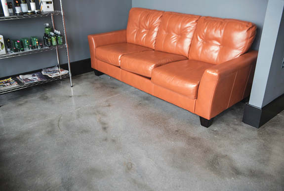 Concrete floor with a decorative look in grays and blacks contrasting an orange leather couch.