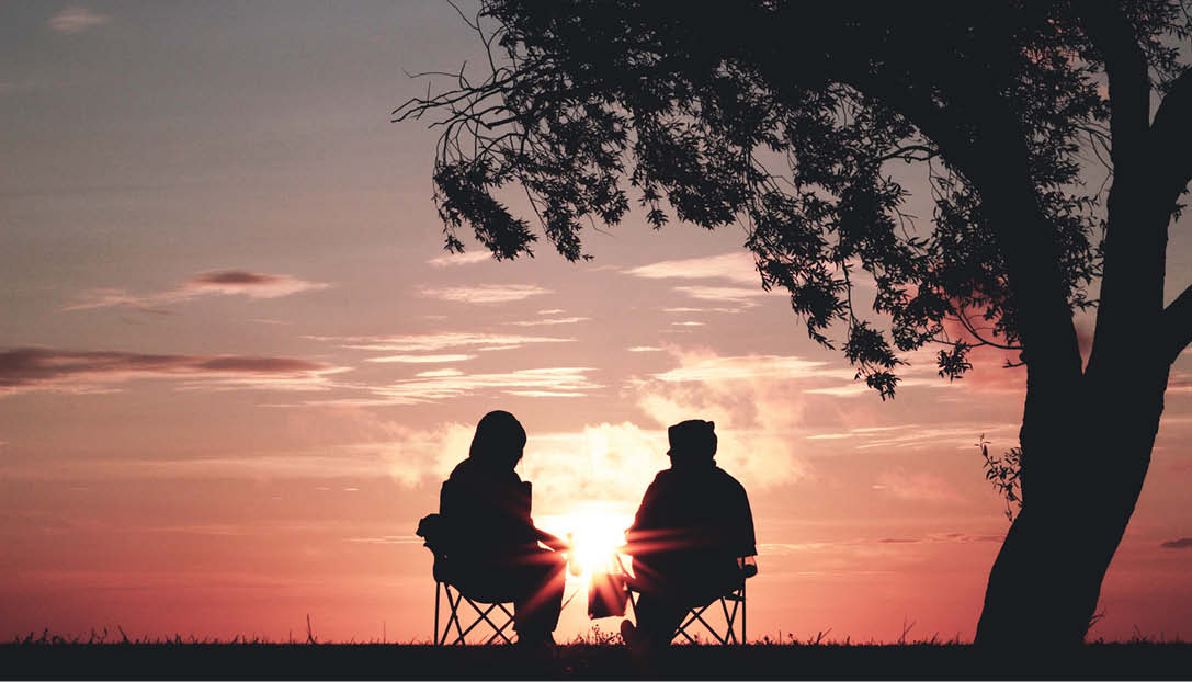 Silhouette of two people sitting enjoying the sunset.
