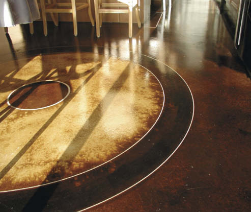The shadows of the outdoor light dance on the circular pattern stained and engraved on this concrete floor.