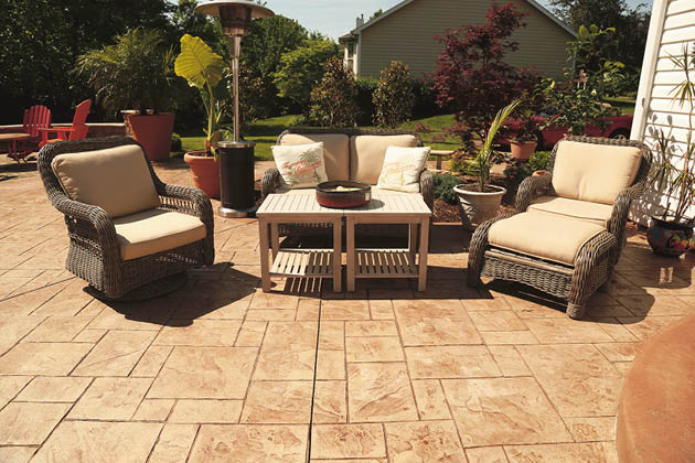 A stamped concrete patio with darker grout lines with patio furniture on it.