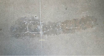 Seen here are drill holes that have been injected with epoxy which has leeched back through the concrete. Note how much wider the delamination area extends beyond the crack lines.