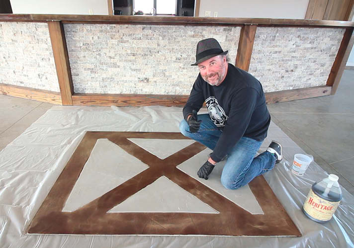 Rick Lobdell posing with his finished project of hand brushing borders on concrete