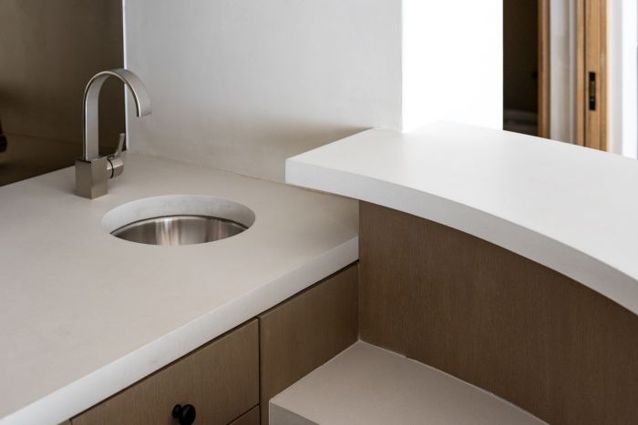 A sink placed in a concrete countertop that has flanked with geometric styles.