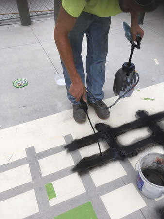 Using a stain and stencil to place color onto a concrete floor.