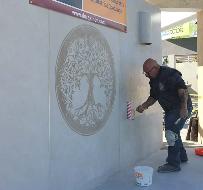 Applying a microtopping on a wall that is flanked with a concrete stencil.