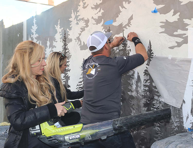 Applying a stencil on a vertical wall to look like trees.