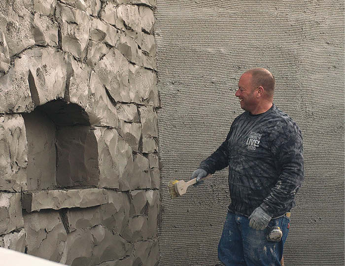 Emil Gera creates textures on his vertical concrete wall that mimics large rocks.