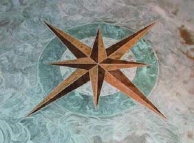Two toned stained concrete compass on blue and light blue stained concrete floor.