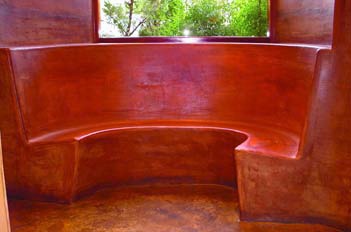 A built-in concrete bench that has been colored with red and brown tones.