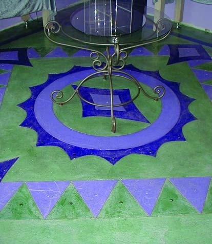 Sage green epoxy coating on a floor with two tones of purple creating a rug with a round glass and metal table inside the circle.