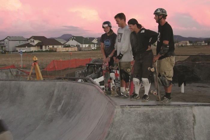 Skateboarders watching a skater doing tricks.