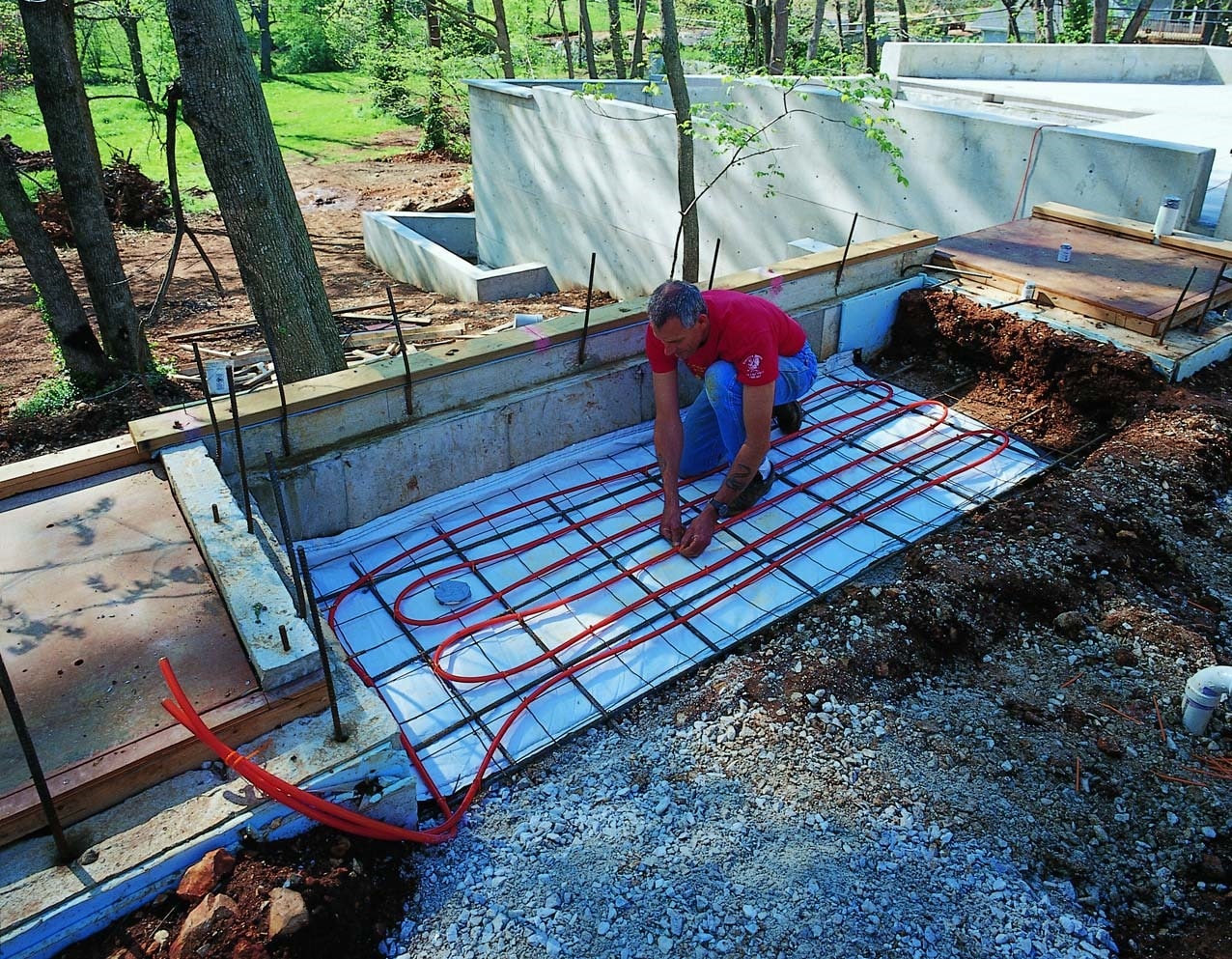 Radiant floor heating tube being placed above the rebar before the concrete is poured.