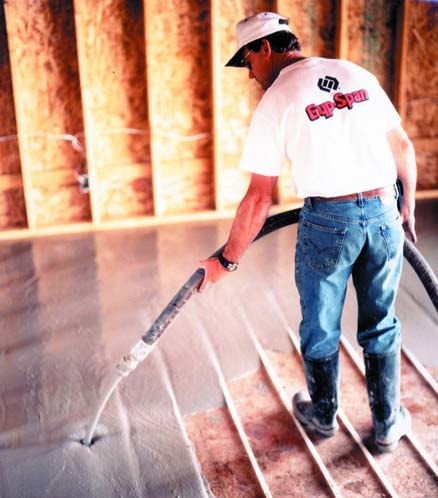 Concrete contractor pouring thin set cementious topping onto a floor with hydronic radiant heating tubes.