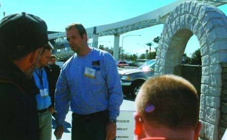 Man talks with attendees at World of Concrete 2003 about his carved concrete archway.