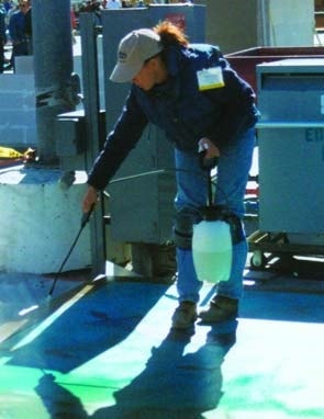 A women spraying concrete acid stain in a sea blue onto a concrete slab at the World of Concrete 2003