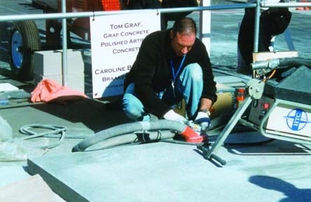 Tom Graf of Graf Concrete polishes a concrete pad at the World of Concrete 2003 with an HTC machine and vacuum.