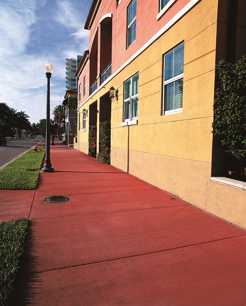 Brushed Concrete Sidewalk in deep red contrasts with a yellow stucco building.