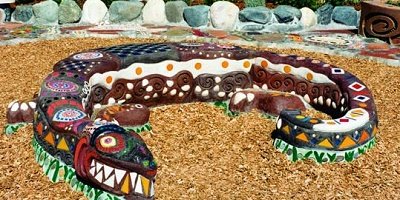 A giant concrete lizard that is decorated with bright colors and design aesthetics like Mexican pottery.