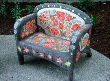 A concrete chair outdoors that has been colored and decorated with a floral design.