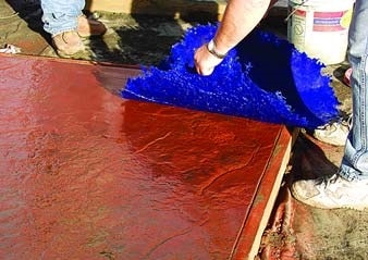 Red concrete being textured with a blue texture skin at a concrete training workshop.