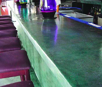 A vibrant green concrete countertop in a high-end bar establishment.