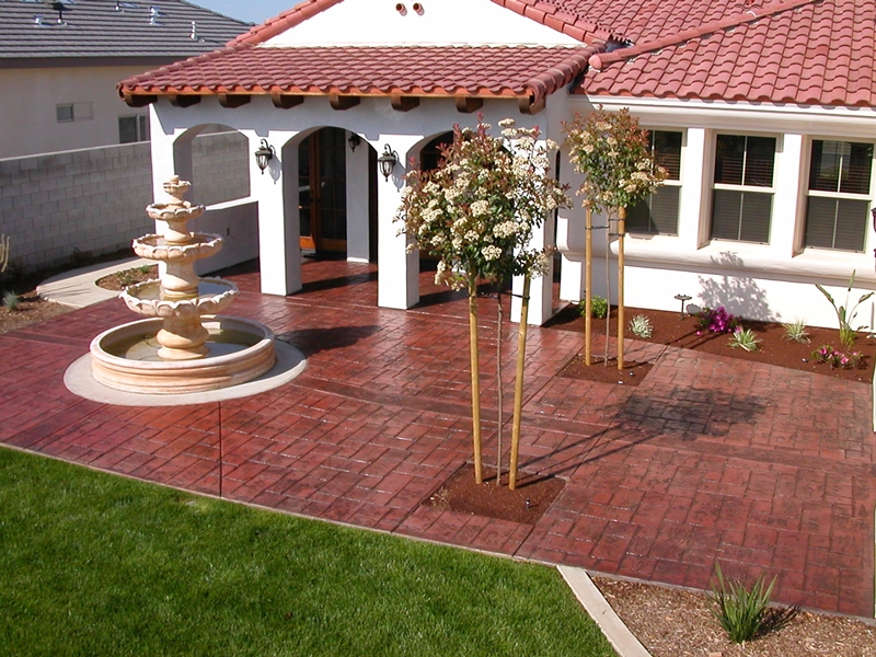 A stamped and stained concrete patio with a large 4 tier water fountain in front.