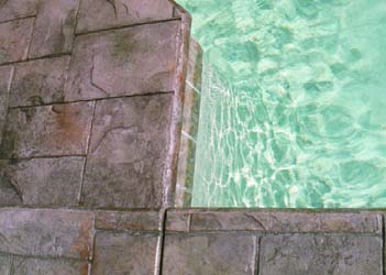 Pool deck with stamped concrete and colored with brown stains.