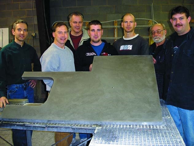 Jeffrey Girard with students holding up a precast concrete countertop at Concrete Countertop Institute.