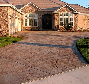 stamped curved driveway - An example of how driveway curves match a residences arches. Notice how naturally the driveway blends with the landscape and culture stone.