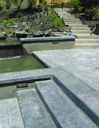 Concrete Steps next to a smooth edged water feature pond.