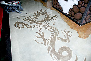 A stencil was used to create this dragon in a deeper acid stained color next to the light concrete floor.