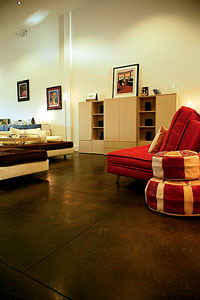 Deep colored concrete floor in a serene living room with a red sitting chair.