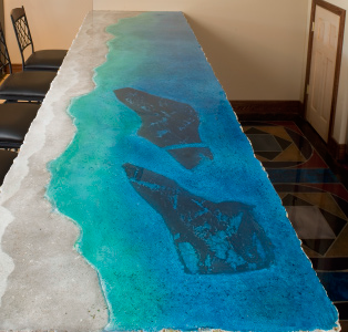 Top view of a concrete counter featuring a ocean theme from deep ocean blue to the sandy beach with shells