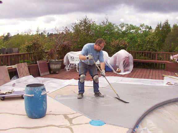 Continuing to apply coating in preparation for stenciling on concrete