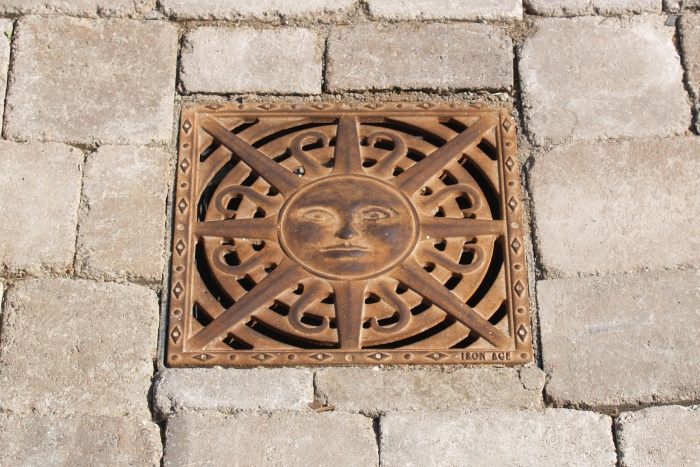 Decorative grate cover in the shape of a sun.