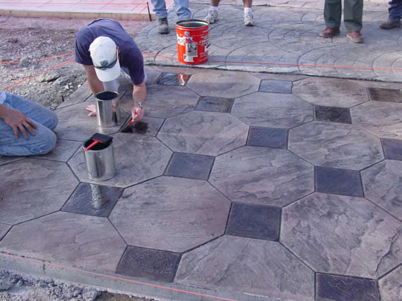 Using acid stain to vary the color of each stone on a stamped concrete slab.