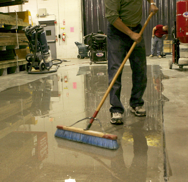 Person applying a finish on concrete flooring with a pushbroom